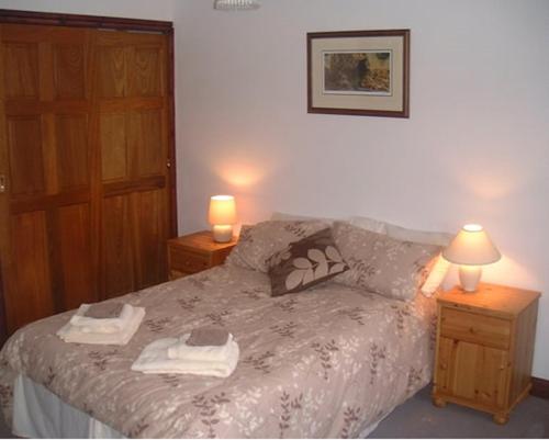 a bedroom with a bed with towels and two lamps at Horseshoe Pass Holiday Lets in Llangollen