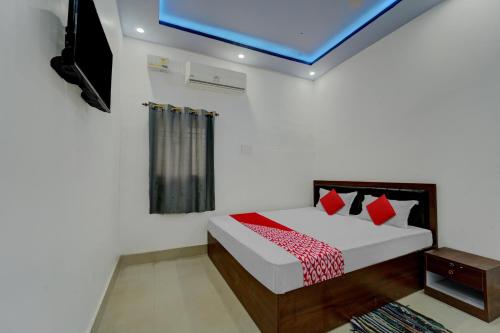 a bedroom with a bed with red pillows and a tv at Hotel O Dev Laxmi Palace Hotel & Banquet in Bihār Sharīf