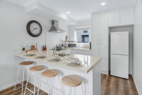 a kitchen with a large white counter with stools at River City Retreat! King Bed & Central - By KOSH BNB in Hamilton