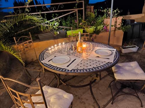 - une table avec des assiettes et des verres à vin sur la terrasse dans l'établissement Love-room Discret 40 m2 Bormes les mimosas village avec Terrasse, à Bormes-les-Mimosas