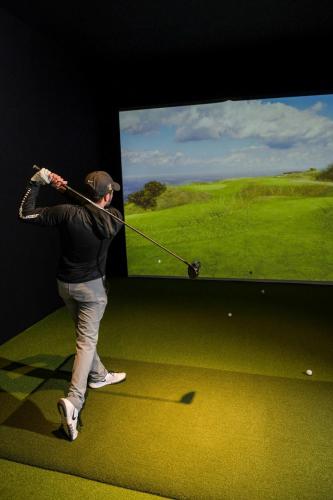 a woman swinging a golf club in front of a screen at Ann Arbor Marriott Ypsilanti at Eagle Crest in Ann Arbor