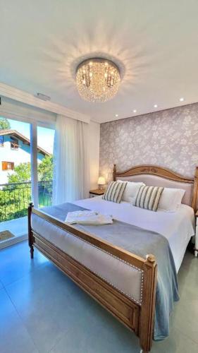 a bedroom with a large bed and a chandelier at Pousada Villa Vie in Gramado