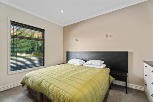 ein Schlafzimmer mit einem Bett mit zwei Kissen und einem Fenster in der Unterkunft Kiwi Ski Cottage - Wanaka Holiday Home in Cardrona