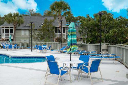 a pool with chairs and a table with a umbrella at Windsor Court - 12B in Spartanburg