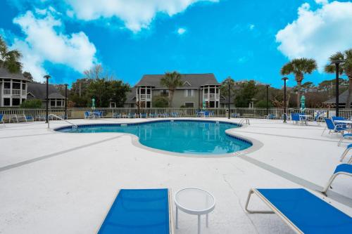 a swimming pool with blue chairs and tables at Windsor Court - 12B in Spartanburg