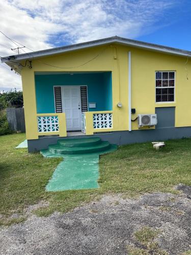 a yellow and blue house with a front porch at Sasha’s Holiday Home Oistins Barbados in Christ Church