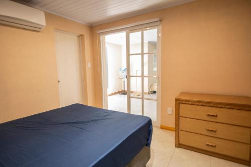a bedroom with a bed and a dresser and a sliding glass door at Complejo Anacahuita in Carmelo