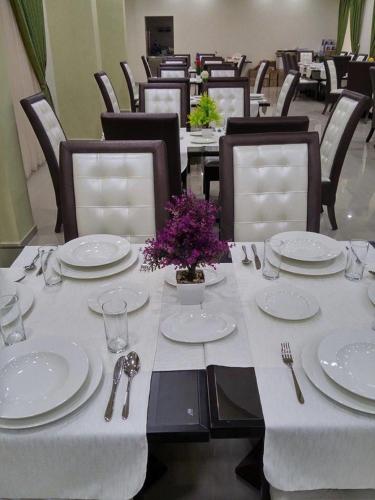a table with white plates and utensils on it at Queen Plaza Hotel in Hebron