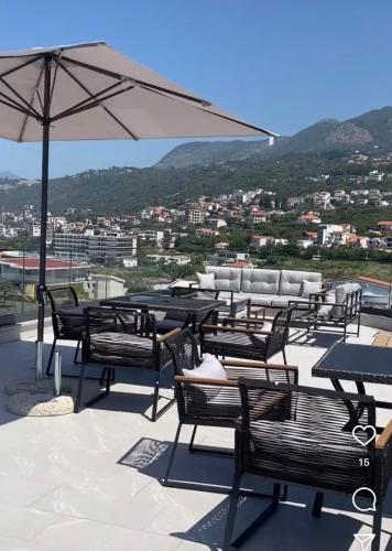 a group of tables and chairs with an umbrella at Fenix Apartmani Dubrava in Dobra Voda