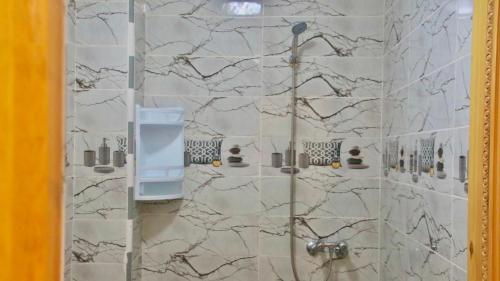 a bathroom with a shower with marble tiles at Résidence dakhla médina in Dakhla