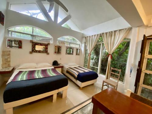 a bedroom with two beds and a desk and windows at Casa del Arquitecto in Cancún