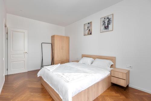 a white bedroom with a large bed with white sheets at Aparthotel Hilton Blox in Tbilisi City