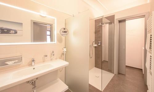 ein Bad mit einem Waschbecken und einer Dusche in der Unterkunft Hotel Mader in Steyr