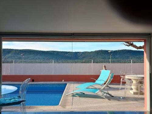 a patio with chairs and a table and a pool at Village House in France with Private Pool in Bagnols-en-Forêt