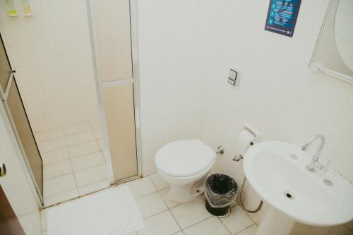 a white bathroom with a toilet and a sink at HOTEL ROYAL PARK in Piracicaba