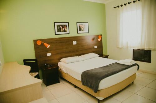 a bedroom with a large bed with a wooden headboard at HOTEL ROYAL PARK in Piracicaba