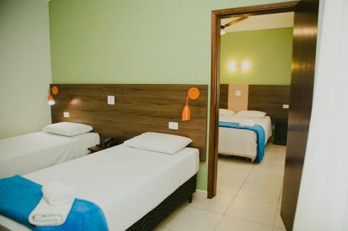a hotel room with two beds and a mirror at HOTEL ROYAL PARK in Piracicaba