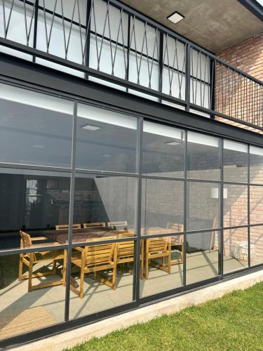 a glass extension of a building with a table and benches at Casa con Alberca privada en Cuernavaca in Ahuatepec