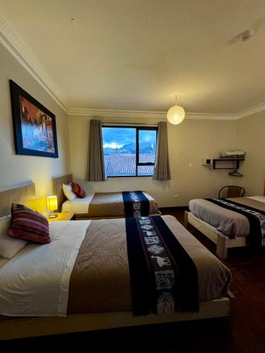 a hotel room with two beds and a window at TATA Hotel Boutique in Cusco