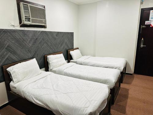 three beds in a room with white sheets and pillows at فندق ألماس المغرب العربي - Almas Maghreb Hotel in Makkah