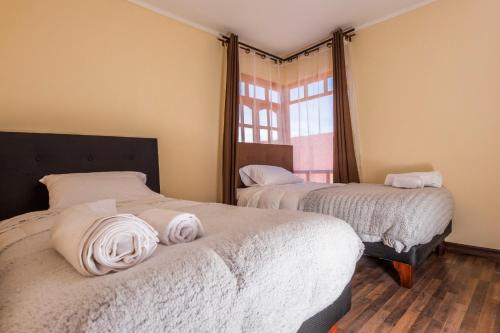 a bedroom with two beds with white sheets and a window at Atacama Cottage in San Pedro de Atacama