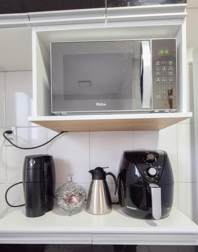 a microwave on a shelf in a kitchen at Ap 3Q, elegante e funcional, com estacionamento in Belém