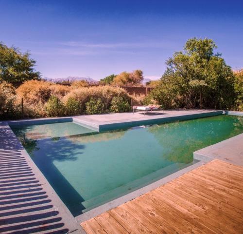 a swimming pool in a yard with a wooden deck at Casa Luna in San Pedro de Atacama