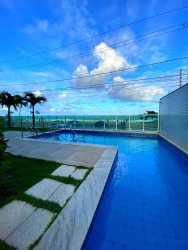 a blue swimming pool with the ocean in the background at Aptº. Beira Mar com Vista Mar. in Recife