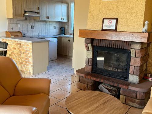 un salon avec une cheminée en briques dans une cuisine dans l'établissement Gîte de plain-pied avec terrasse, proche port et station thermale, idéal pour familles - FR-1-589-24, à Fontenoy-le-Château