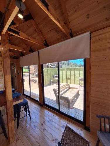 a large window in a cabin with a patio at Acuarela minicasas con piscina en Lago Vichuquen in Vichuquén