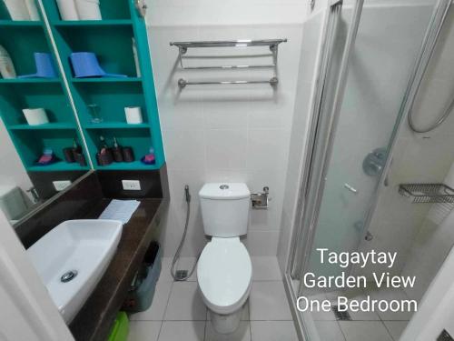 a bathroom with a toilet and a shower and a sink at Tagaytay Cozy 1BR Wind Residences in Kaybagal