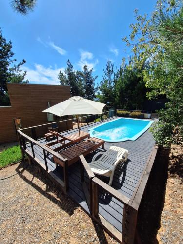 a deck with an umbrella and a swimming pool at Acuarela minicasas con piscina en Lago Vichuquen in Vichuquén