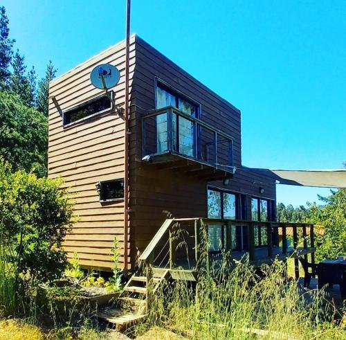 a tiny house with a large window and stairs at Acuarela minicasas con piscina en Lago Vichuquen in Vichuquén