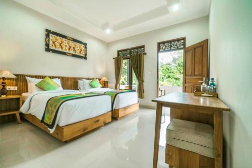 a bedroom with a bed and a desk and a window at Esty House in Ubud