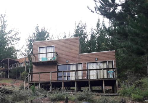 a large wooden house on a hill with trees at Acuarela minicasas con piscina en Lago Vichuquen in Vichuquén