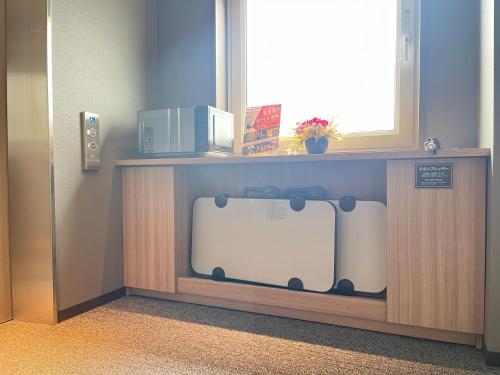 a tv on a shelf in a room with a window at Hotel Route Inn Suzaka in Suzaka
