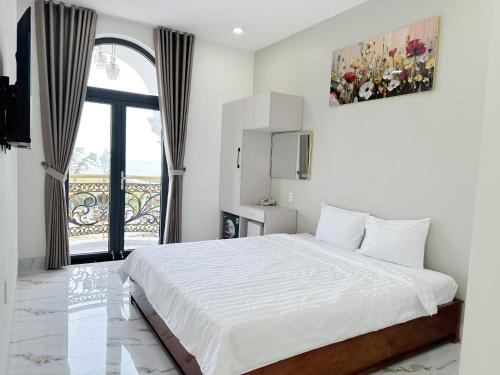 a white bedroom with a bed and a window at Anh Thư Hotel in Ấp Bình Hưng