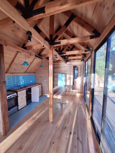a large room with wooden flooring and large windows at Acuarela minicasas con piscina en Lago Vichuquen in Vichuquén