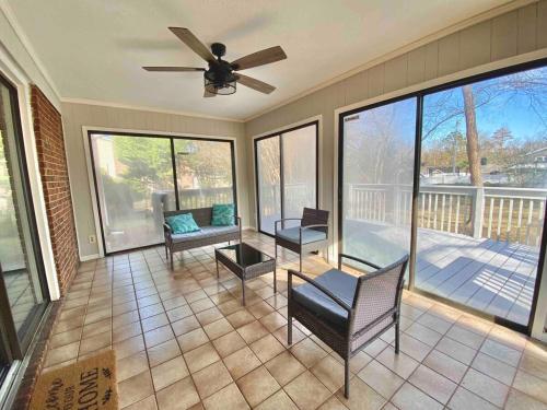 a screened in porch with a ceiling fan and chairs at New Modern Lux Large Home 10MIN Downtown Sleeps 12 in Taylors