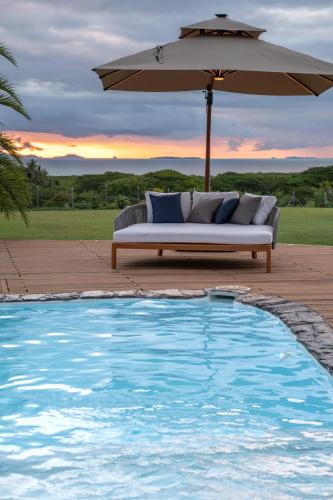a couch sitting under an umbrella next to a pool at Luxury Hilltop Dual Villas With Stunning Sea Views & Pools ! in Lauwaki