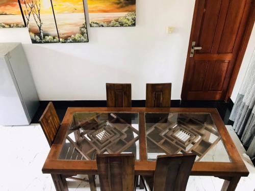 a dining room table and chairs with a glass top at Dreams Villa in Beruwala