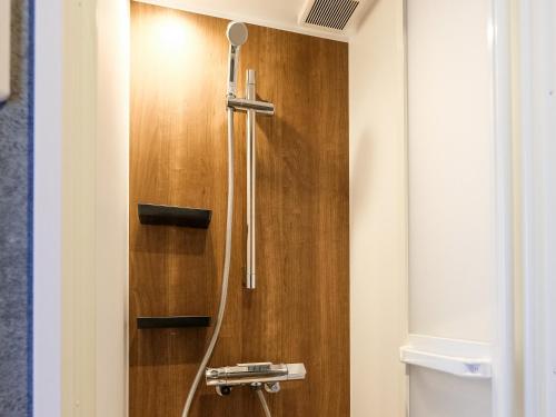 a shower in a bathroom with a wooden wall at Houei Ryokan in Fukui