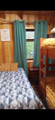 a bedroom with a bed and a window with green curtains at Patagon karim in Puerto Cahacabuco