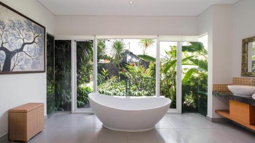 a bathroom with a large tub in front of a window at Villa Yenian by Villa Finder in Canggu