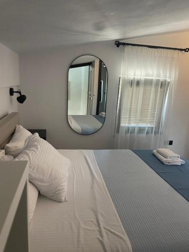 a bedroom with a large white bed and a mirror at Allure Luxury Villas 2, Skiathos in Skiathos Town