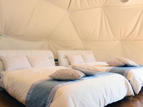 two beds in a tent with pillows on them at Minamiaso BlueBeeGarden in Minami Aso