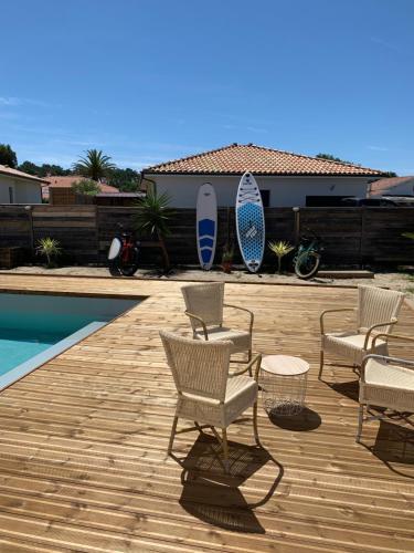 - une terrasse avec des chaises et des planches de surf à côté de la piscine dans l'établissement Sewa surf House 10min de Capbreton 1, à Bénesse-Maremne