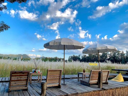 two tables and two chairs with umbrellas on a deck at T Villas Kaeng Khoi in Sara Buri