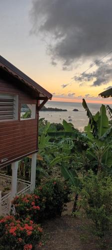 a house with a view of the beach at sunset at Issa Blue Appartement Vue sur Mer in Bouillante