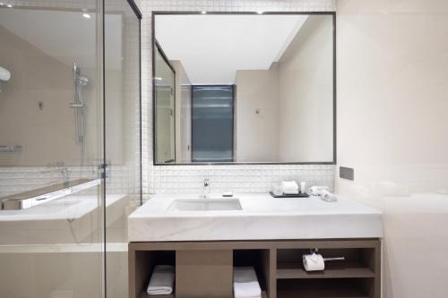 a bathroom with a sink and a mirror and a tub at Hyatt House Shanghai Hongqiao CBD in Shanghai